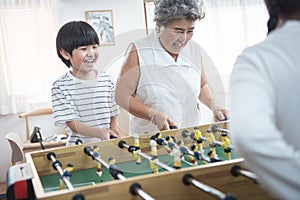Group of diversity aged family playing soccer table game together happily. Grandmother playing game together with her children at