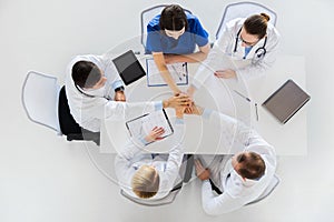 Group of doctors holding hands together at table