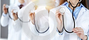 Group of doctors holding stethoscope head, close-up. Physicians ready to examine and help patient in sunny office