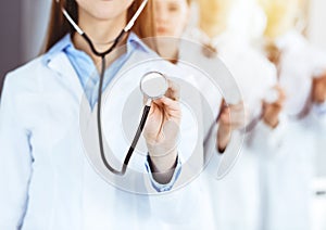 Group of doctors holding stethoscope head, close-up. Physicians ready to examine and help patient in sunny office