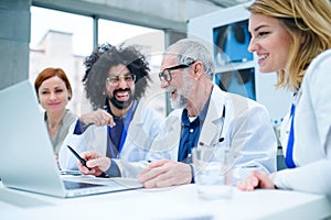 Group of doctors with laptop on conference, medical team discussing issues.