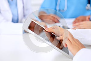 Group of doctors at medical meeting. Close up of physician using tablet computer.