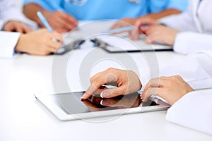 Group of doctors at medical meeting. Close up of physician using tablet computer.