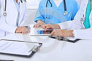 Group of doctors at medical meeting. Close up of physician using touch pad or tablet computer