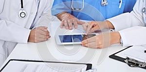 Group of doctors at medical meeting. Close up of physician using touch pad or tablet computer