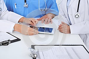 Group of doctors at medical meeting. Close up of physician using touch pad or tablet computer