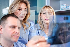 Group of doctors and nurses looking to and discussing x-ray image at clinic.