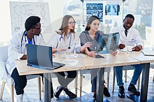 Group of doctors are studying disease patient`s history. Team of multiethnic young doctors having a meeting in