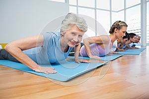 Group doing cobra pose in row at yoga class