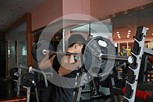 Fitness man in the gym doing squat . Man with dumbbell weight training equipment gym. Indoor, instructor.