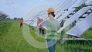 Group of ecological engineers and assistant walking through the photovoltaic solar farm they analysing the operation of