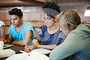 Group, education and students writing in notes studying for exam or learning information in classroom. University