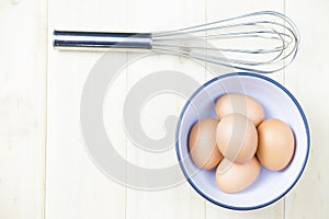 Group of eggs in bowl whisk on wooden table topview flat lay wit