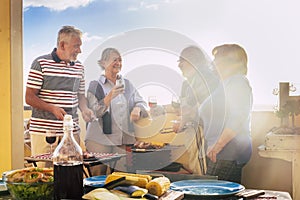 Group of elderly people have fun in frienship outdoor cooking a bbq all together. Senior couples friends enjoy leisure time eating