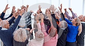 a group of elderly people are reaching up