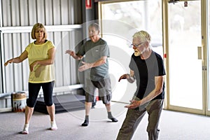 Group of elderly senior people practicing Tai chi class in age care gym facilities