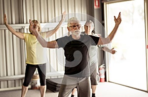 Group of elderly senior people practicing Tai chi class in age care gym facilities