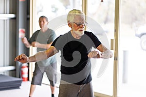 Group of elderly senior people practicing Tai chi class in age care gym facilities