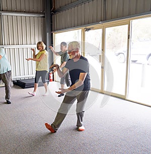 Group of elderly senior people practicing Tai chi class in age care gym facilities