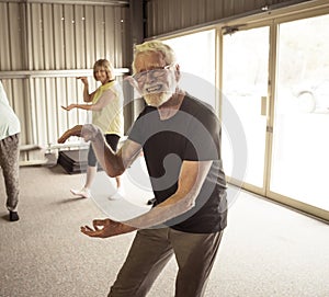 Group of elderly senior people practicing Tai chi class in age care gym facilities