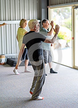 Group of elderly senior people practicing Tai chi class in age care gym facilities