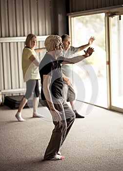 Group of elderly senior people practicing Tai chi class in age care gym facilities