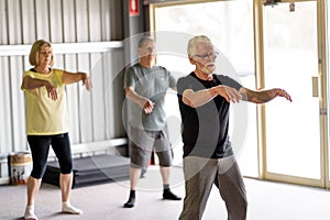 Group of elderly senior people practicing Tai chi class in age care gym facilities