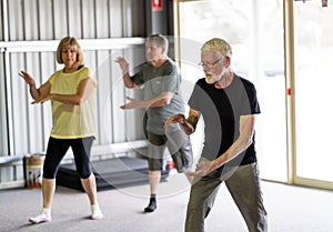 Group of elderly senior people practicing Tai chi class in age care gym facilities