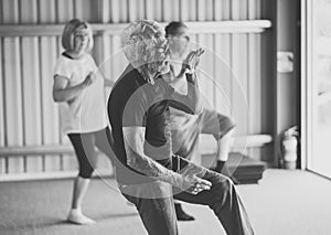 Group of elderly senior people practicing Tai chi class in age care gym facilities