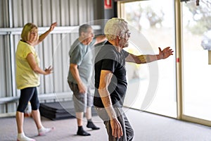 Group of elderly senior people practicing Tai chi class in age care gym facilities