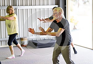 Group of elderly senior people practicing Tai chi class in age care gym facilities