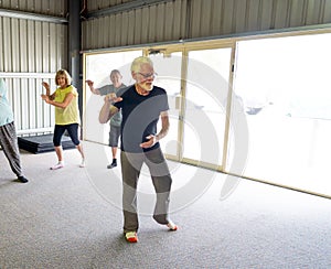 Group of elderly senior people practicing Tai chi class in age care gym facilities