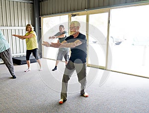 Group of elderly senior people practicing Tai chi class in age care gym facilities