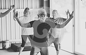 Group of elderly senior people practicing Tai chi class in age care gym facilities