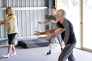 Group of elderly senior people practicing Tai chi class in age care gym facilities