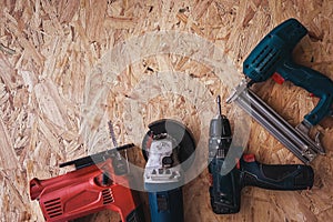 Group of electric hand tools jigsaw, grinder, drill, nail gun and white safety helmet on wooden background