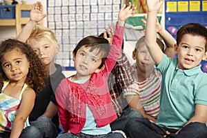 Group Of Elementary Age Schoolchildren Answering Question In Class