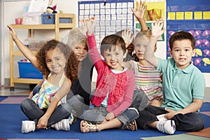 Group Of Elementary Age Schoolchildren Answering Question In Class