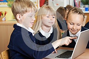 Group Of Elementary School Children Working Together In Computer