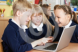 Group Of Elementary School Children Working Together In Computer
