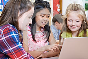 Group Of Elementary School Children Working Together In Computer