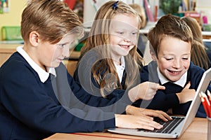 Group Of Elementary School Children Working Together In Computer