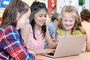 Group Of Elementary School Children Working Together In Computer