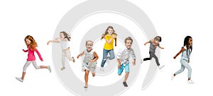Group of elementary school kids or pupils running in colorful casual clothes on white studio background. Creative