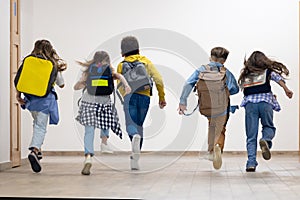 Group of elementary school kids running in school corridor.