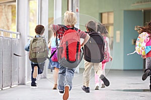 Group of elementary school kids running at school, back view