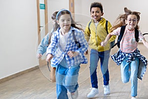 Group of elementary school kids running in school corridor.