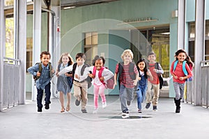 Group of elementary school kids running in a school corridor