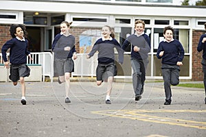 Group Of Elementary School Pupils Running In Playground photo