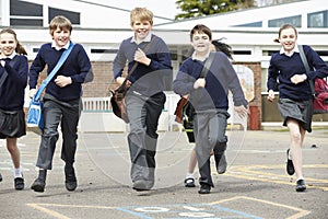 Group Of Elementary School Pupils Running In Playground